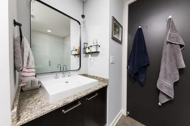 a bathroom with a granite countertop sink a mirror and shower