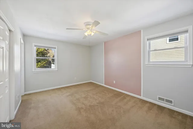 an empty room with windows and fan