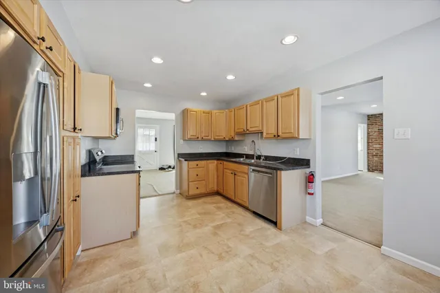 a kitchen with granite countertop a refrigerator and a stove top oven