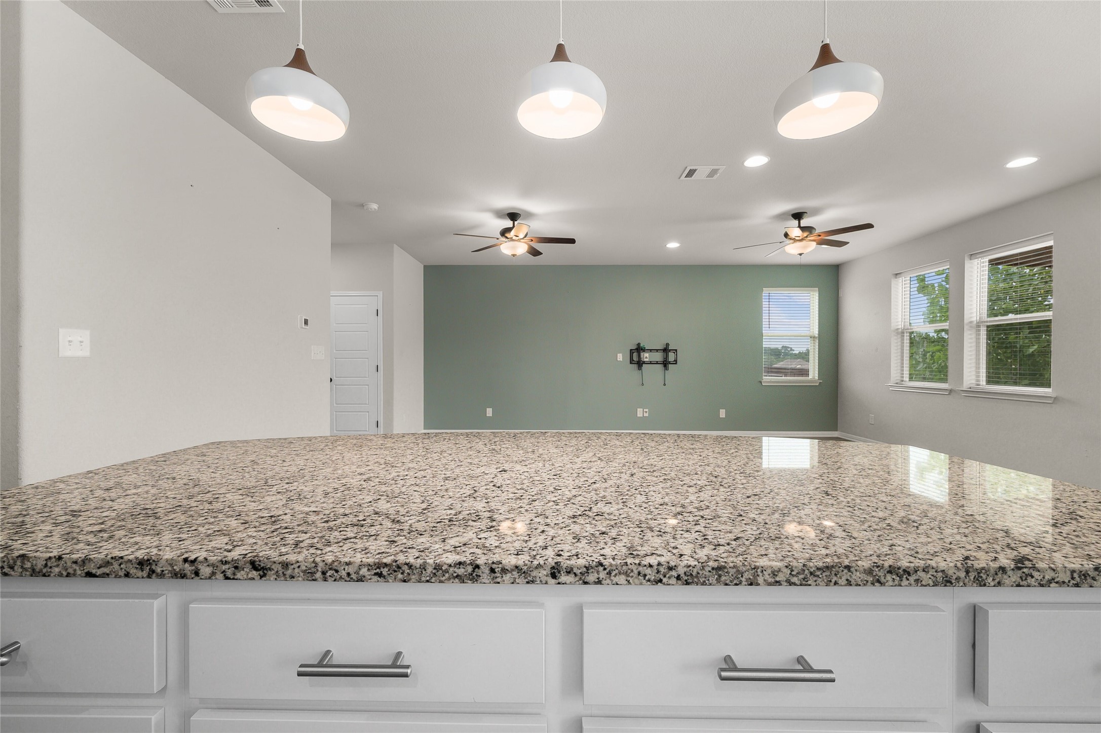 101 Lambert Street Leander, TX 78641 - Photo 14 of 33 A well-lit kitchen island with granite counters overlooking a versatile living space, perfect for entertaining.