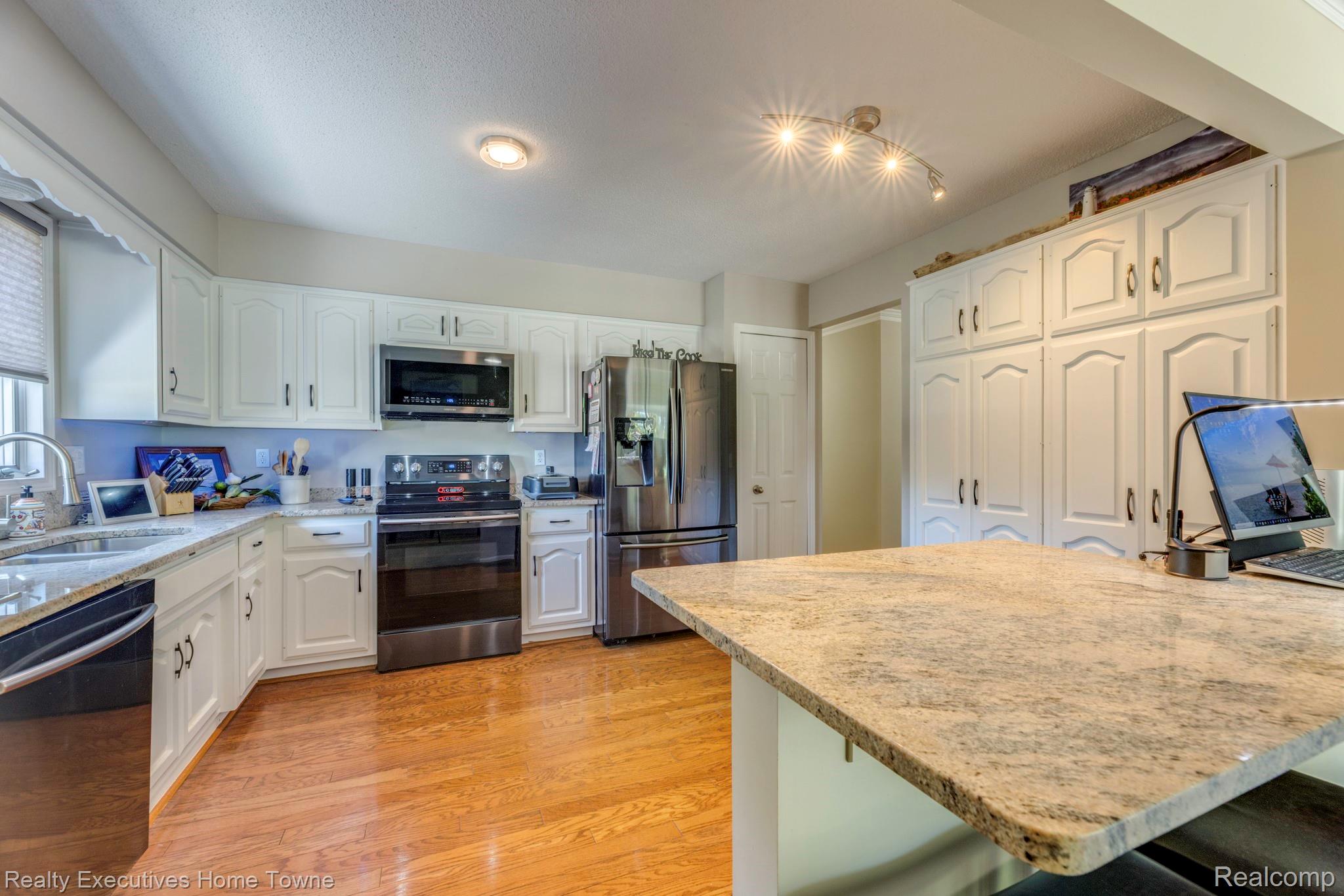 1467 Krafft Road, Unit 8 Port Huron, MI 48060 - Photo 11 of 30 Bright kitchen featuring extensive white cabinetry, stainless steel appliances, speckled stone countertops, and wood-finish flooring