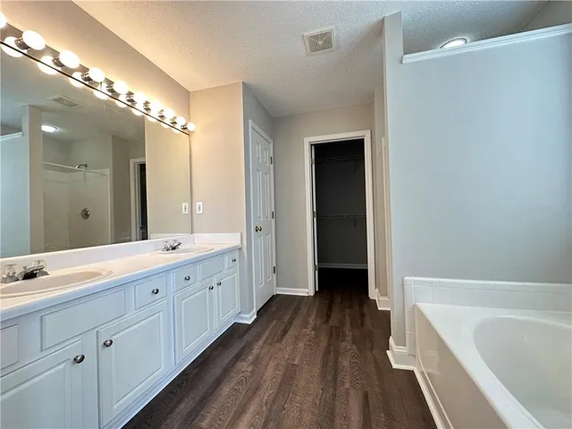 a spacious bathroom with a double vanity sink a large mirror and a bathtub