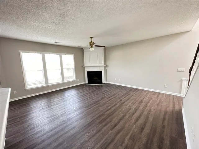 an empty room with wooden floor fireplace and windows