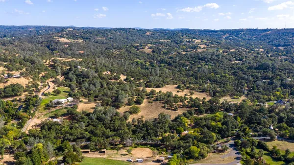 an aerial view of residential houses with outdoor space and trees