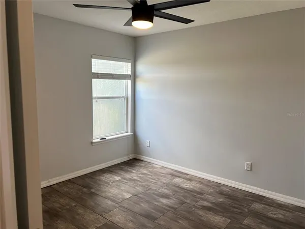 an empty room with a window and ceiling fan
