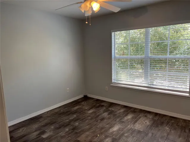 a view of an empty room with window and chandelier fan