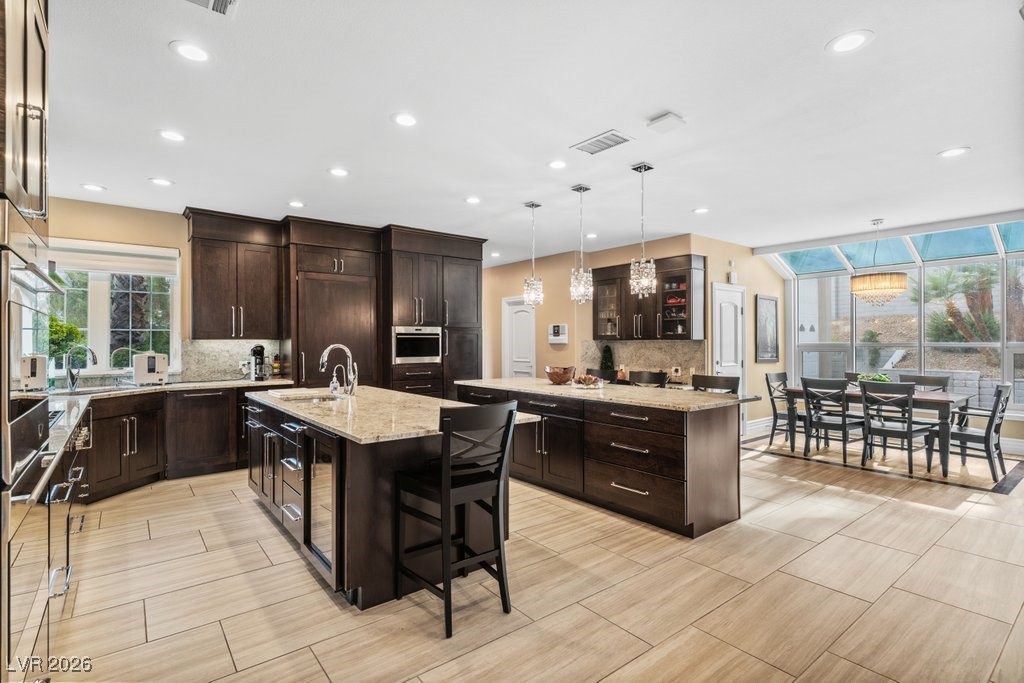 7 Larkside Court Henderson, NV 89014 - Photo 12 of 70 Kitchen with hanging light fixtures, dark brown cabinetry, light stone counters, appliances with stainless steel finishes, and recessed lighting