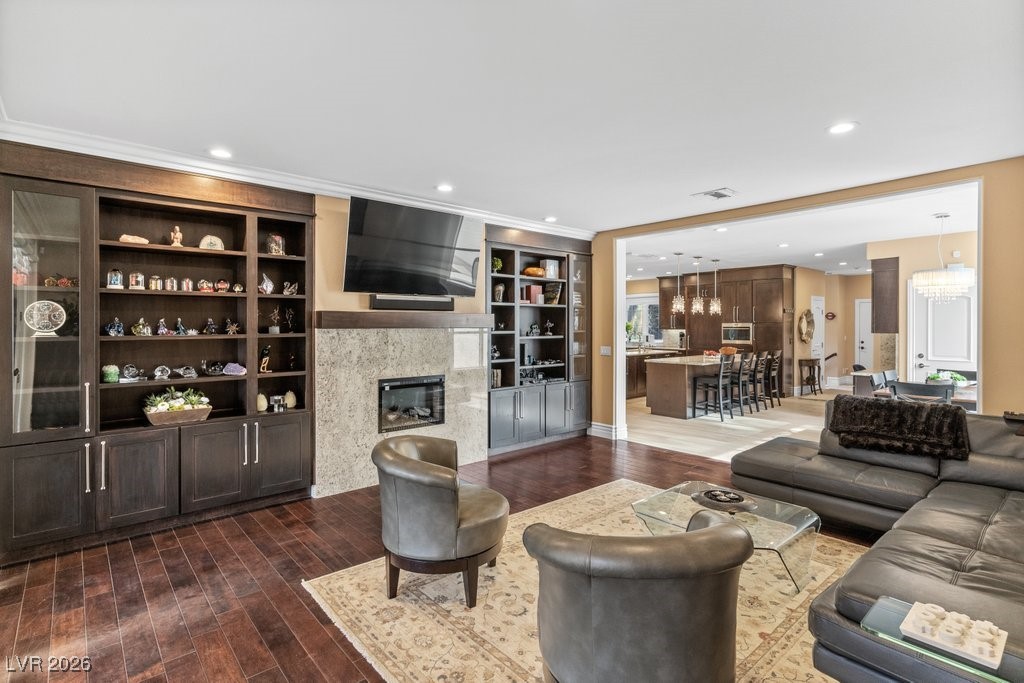 7 Larkside Court Henderson, NV 89014 - Photo 19 of 70 Living area featuring built in shelves, a premium fireplace, dark wood-style flooring, recessed lighting, and a chandelier