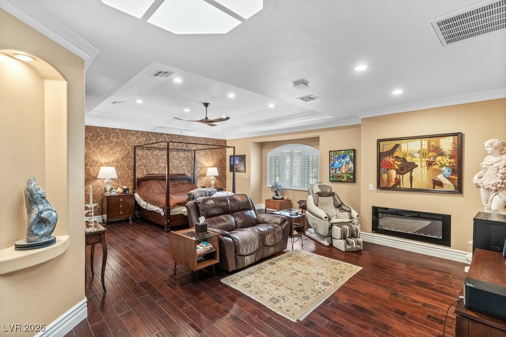 7 Larkside Court Henderson, NV 89014 - Photo 27 of 70 Bedroom with ornamental molding, dark wood-style flooring, a glass covered fireplace, a skylight, and a raised ceiling