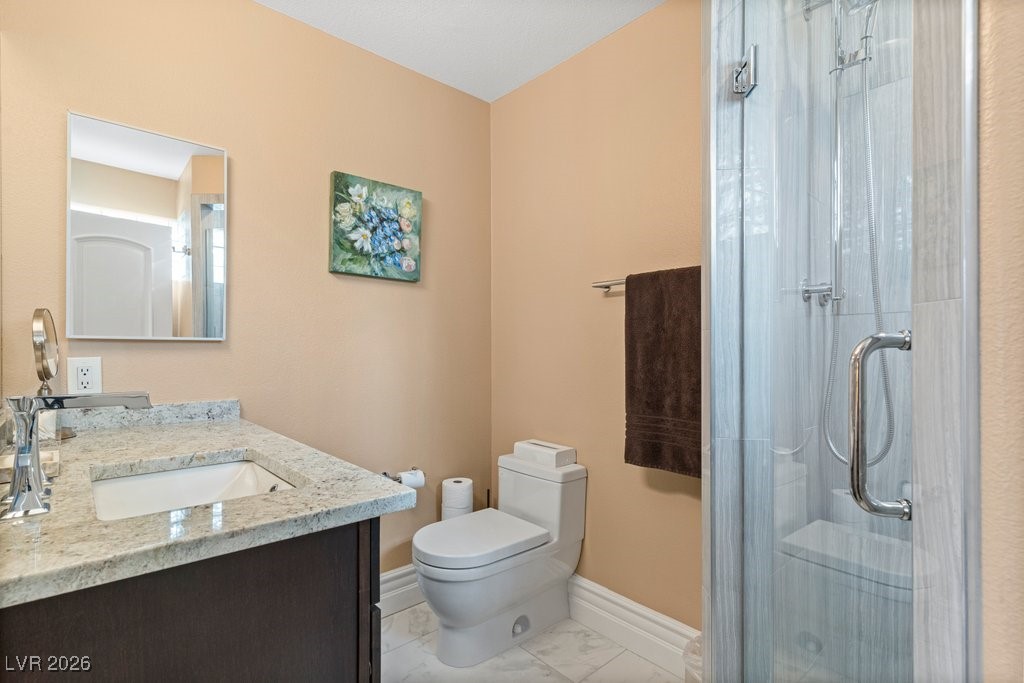 7 Larkside Court Henderson, NV 89014 - Photo 42 of 70 Bathroom featuring a stall shower, vanity, and light marble finish floors