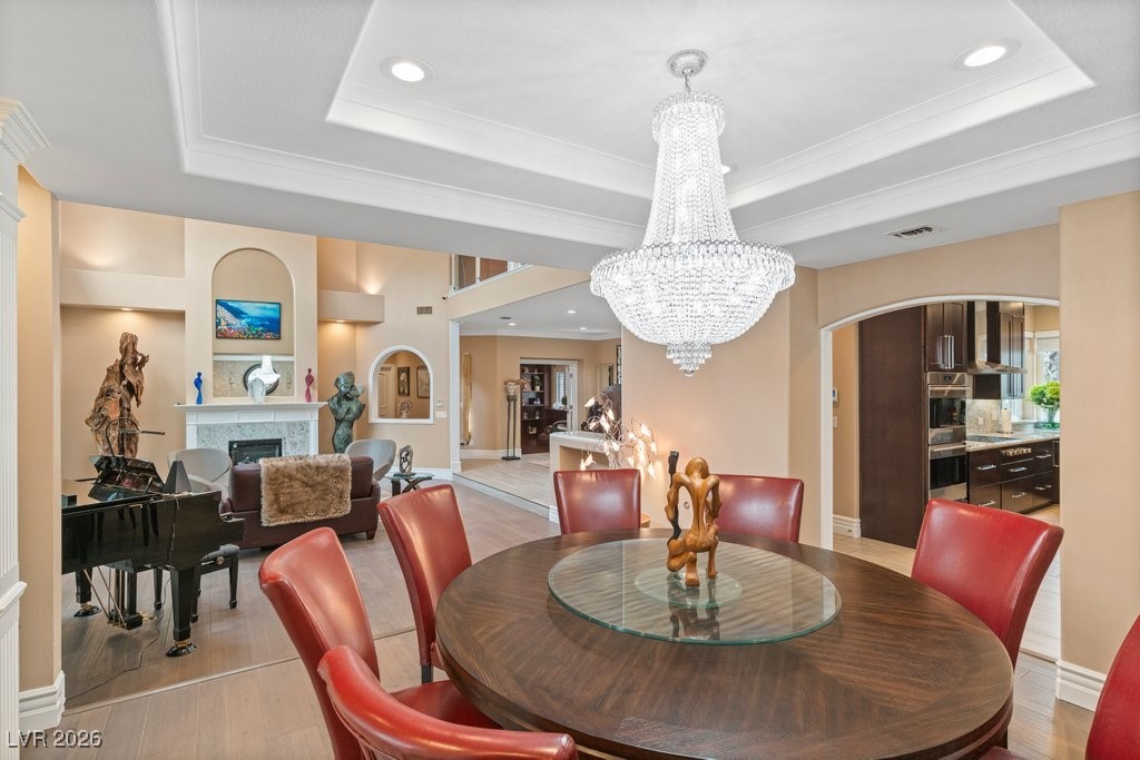 7 Larkside Court Henderson, NV 89014 - Photo 6 of 70 Dining area with a fireplace, recessed lighting, ornamental molding, a chandelier, and arched walkways