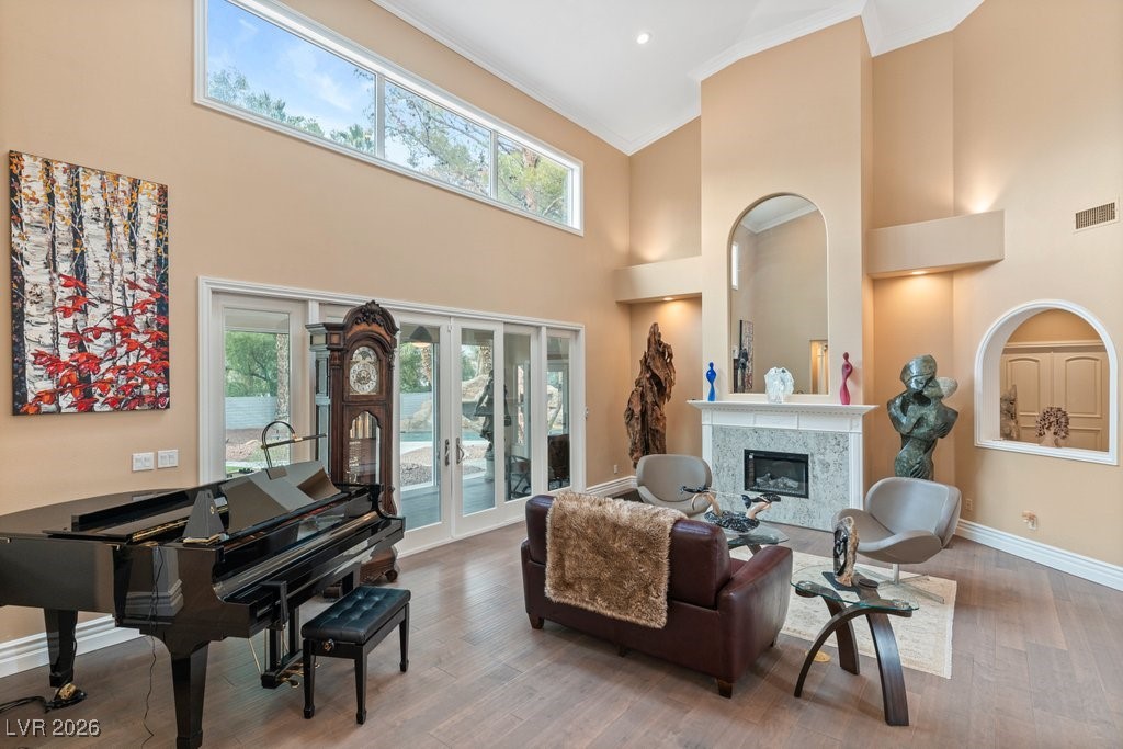 7 Larkside Court Henderson, NV 89014 - Photo 8 of 70 Sitting room featuring ornamental molding, a premium fireplace, wood finished floors, a towering ceiling, and french doors