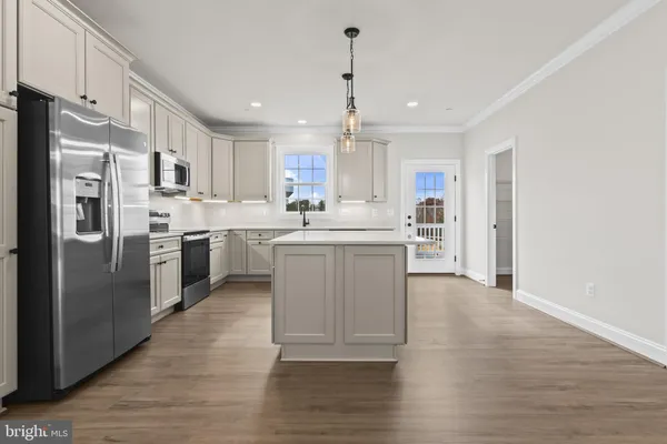 a kitchen with stainless steel appliances granite countertop a refrigerator a sink dishwasher a stove with white cabinets and wooden floor