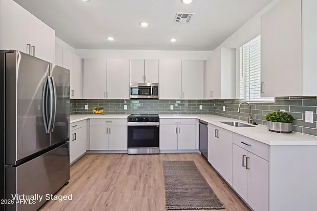 a kitchen with a refrigerator a stove top oven a sink and cabinets