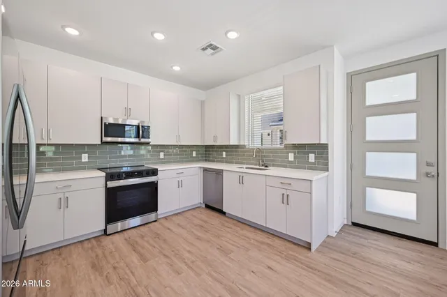 a white kitchen with granite countertop stainless steel appliances