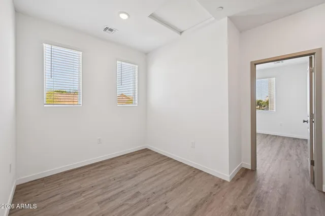 an empty room with wooden floor and windows