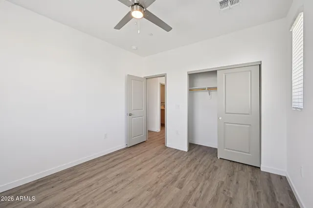 an empty room with wooden floor closet and windows