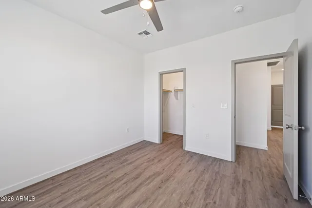 an empty room with wooden floor and a ceiling fan