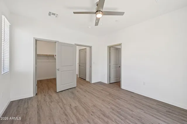 an empty room with wooden floor closet and windows