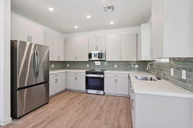 a kitchen with a refrigerator sink and white cabinets