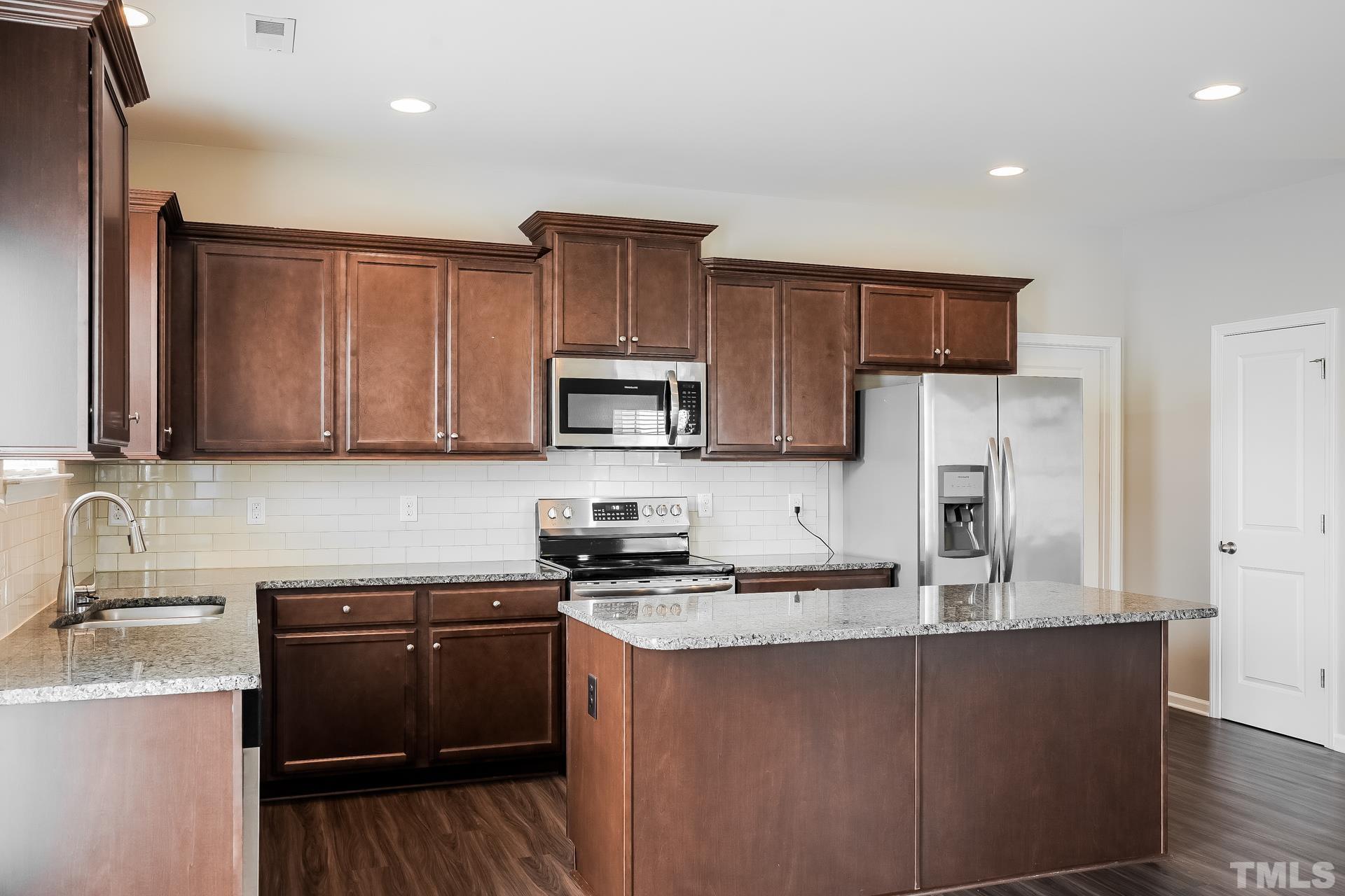 901 Rose Mallow Drive Zebulon, NC 27597 - Photo 6 of 15 a kitchen with kitchen island granite countertop a sink cabinets and stainless steel appliances