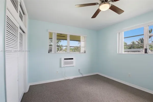 an empty room with windows and fan