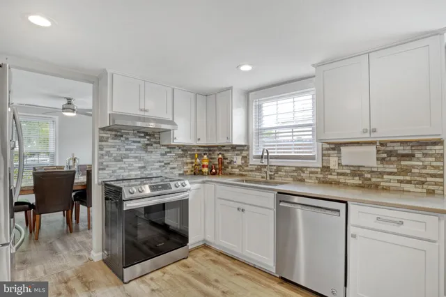 a kitchen with stainless steel appliances granite countertop a stove top oven a sink dishwasher and a refrigerator