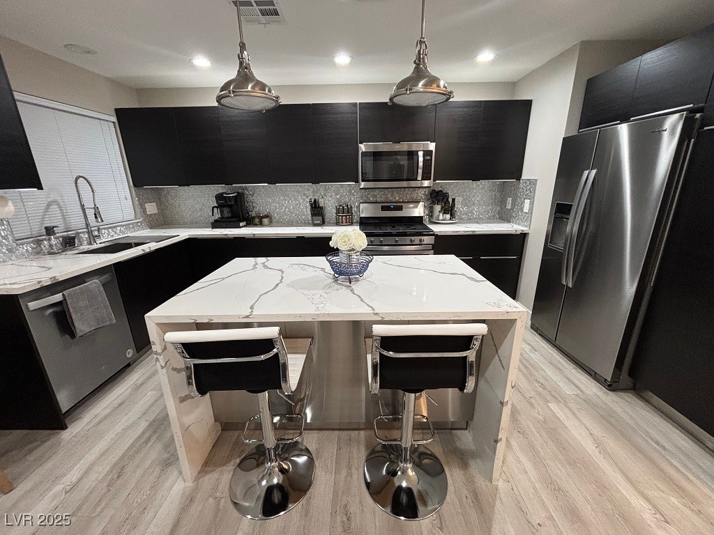 2784 Fountain Ridge Lane Henderson, NV 89074 - Photo 2 of 37 Kitchen with dark cabinetry, light stone counters, decorative light fixtures, a breakfast bar, and recessed lighting