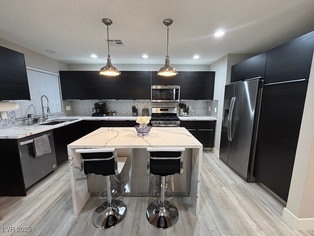 2784 Fountain Ridge Lane Henderson, NV 89074 - Photo 7 of 37 Kitchen featuring dark cabinetry, light stone countertops, decorative light fixtures, stainless steel appliances, and recessed lighting