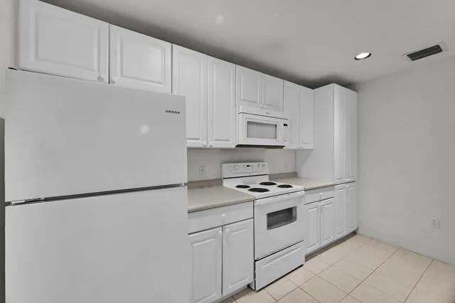 a kitchen with white cabinets and white appliances