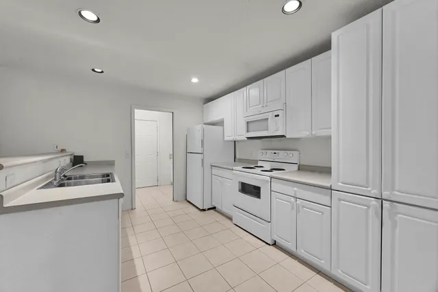 a kitchen with white cabinets stove and sink