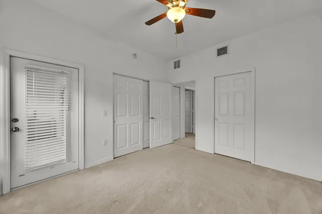 an empty room with a chandelier fan and closet
