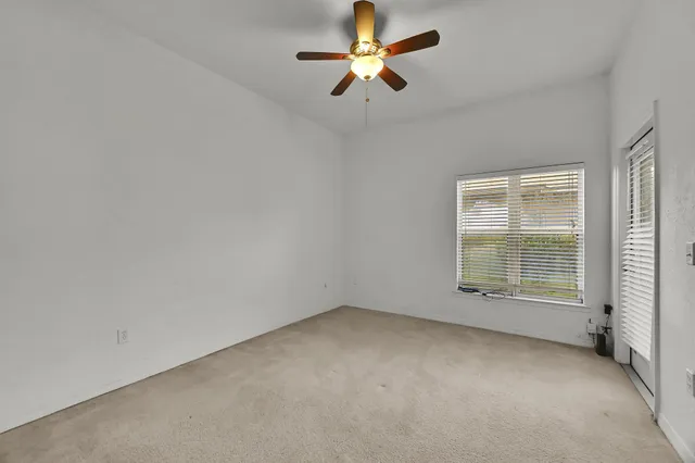 an empty room with a window and a fan