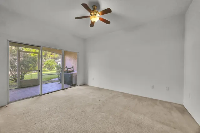 an empty room with floor to ceiling window and an ceiling fan