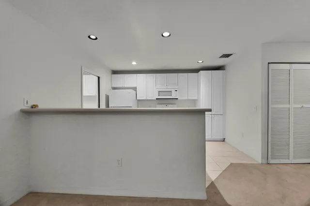 a view of a kitchen with refrigerator and white cabinets