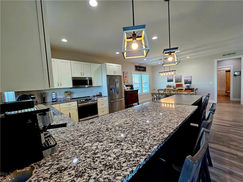 122 Ridge Harbor Drive Rockport, TX 78382 - Photo 17 of 34 a kitchen with stainless steel appliances kitchen island granite countertop a stove top oven a sink a counter top space and cabinets