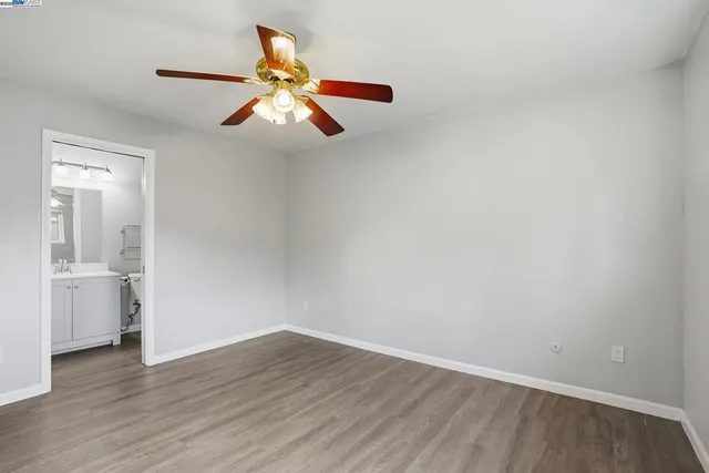 an empty room with wooden floor chandelier fan and windows