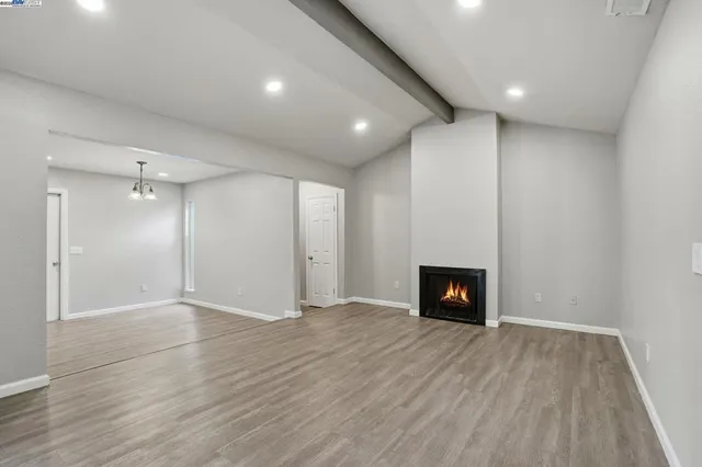 a view of empty room with wooden floor and a fireplace