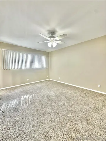 an empty room with a ceiling fan and window