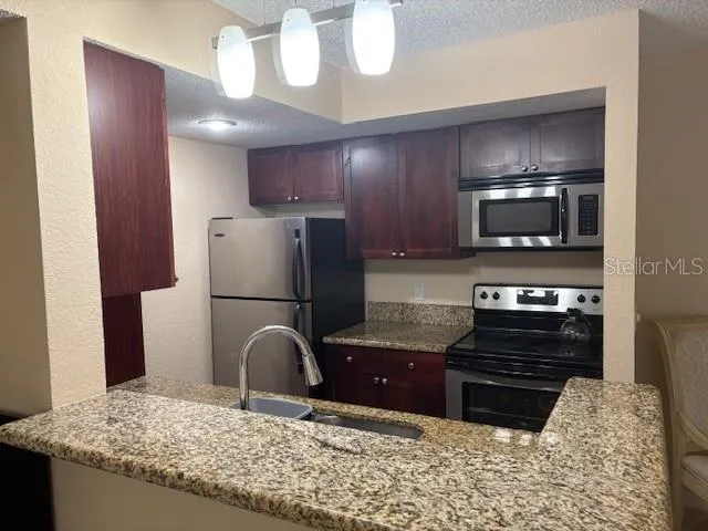 a kitchen with granite countertop a stove and a refrigerator