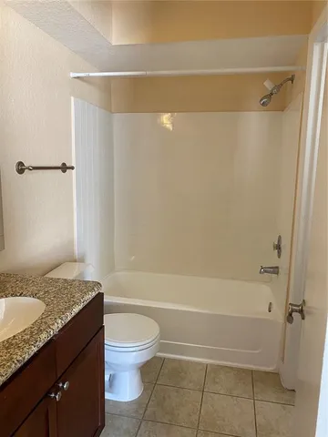 a bathroom with a granite countertop bathtub shower sink vanity and toilet