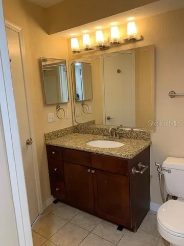 a bathroom with a granite countertop sink toilet and mirror