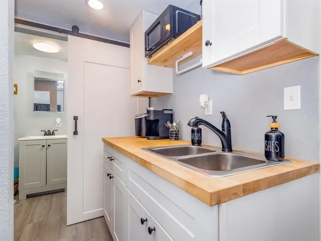 a kitchen with sink a microwave and cabinets