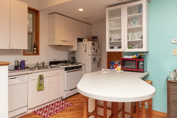 a kitchen with stainless steel appliances a stove a sink a refrigerator and white cabinets with wooden floor