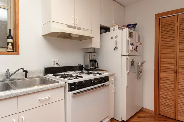 a kitchen with stainless steel appliances a refrigerator a sink and white cabinets