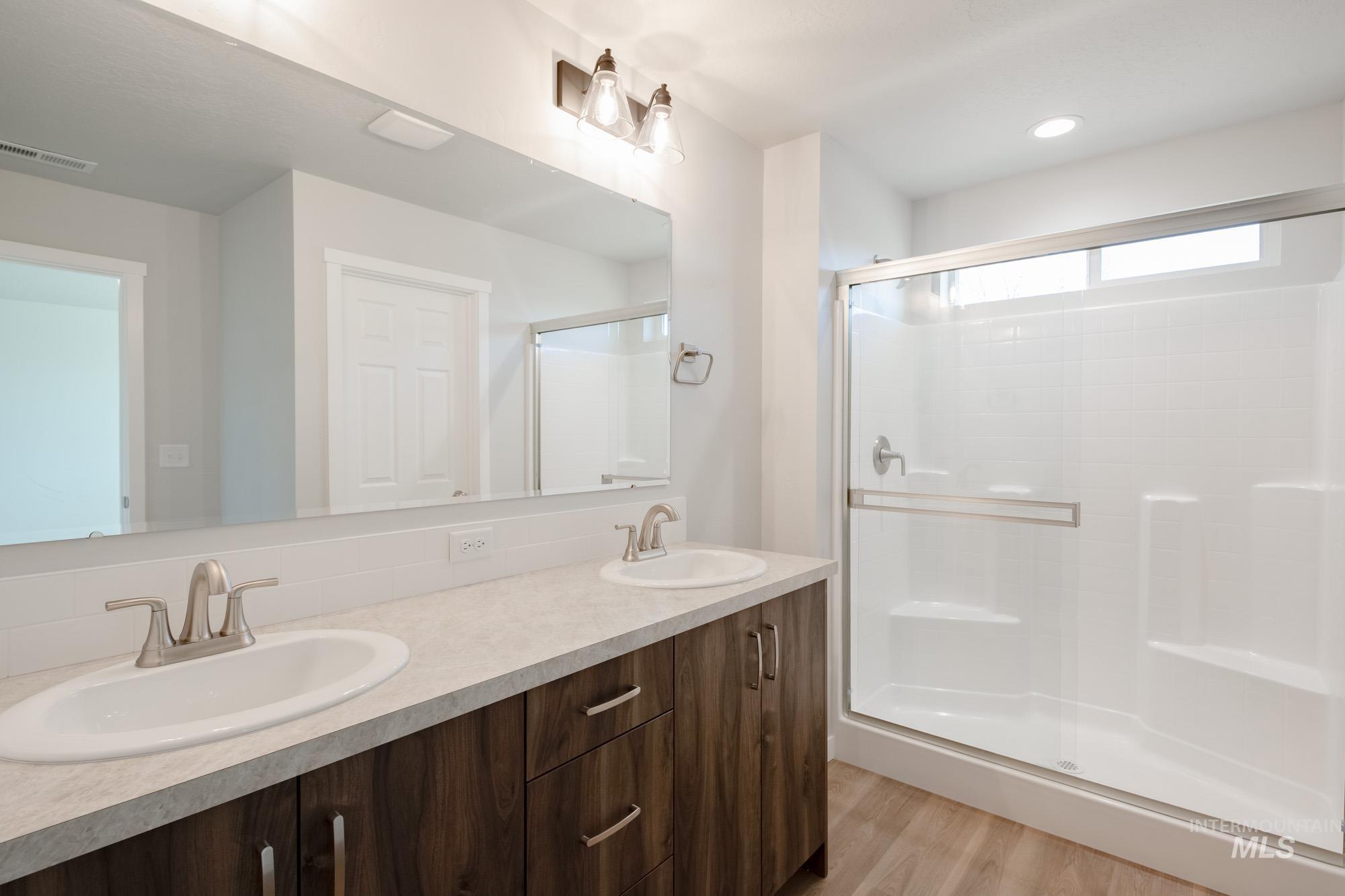 3290 South Maple Rnch Way Nampa, ID 83686 - Photo 15 of 20 Bathroom featuring double vanity, a stall shower, and light wood-style flooring