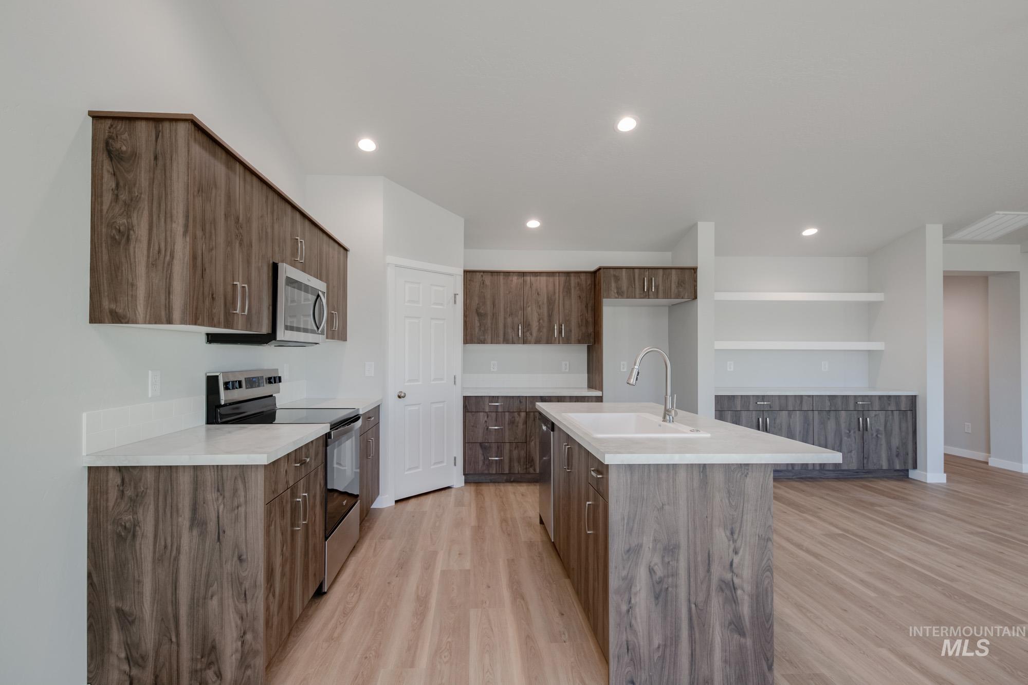 3290 South Maple Rnch Way Nampa, ID 83686 - Photo 4 of 20 Kitchen with appliances with stainless steel finishes, a center island with sink, light wood-type flooring, recessed lighting, and modern cabinets