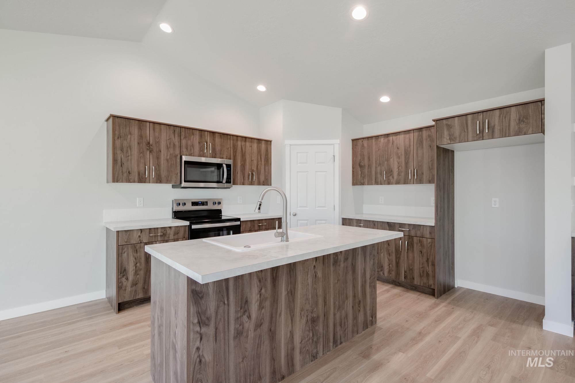 3290 South Maple Rnch Way Nampa, ID 83686 - Photo 7 of 20 Kitchen featuring lofted ceiling, light countertops, stainless steel appliances, a center island with sink, and light wood-type flooring