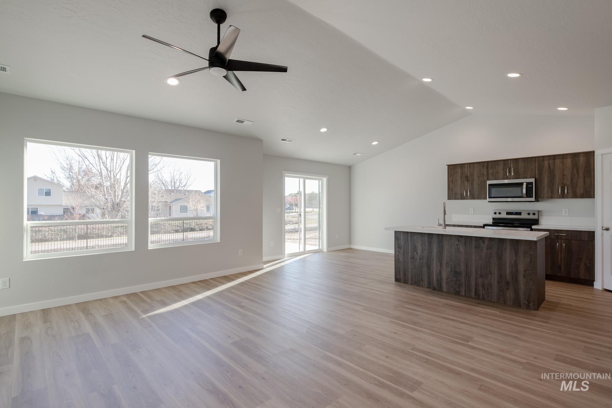 3290 South Maple Rnch Way Nampa, ID 83686 - Photo 20 of 20 Kitchen with light countertops, open floor plan, a kitchen island with sink, dark brown cabinetry, and ceiling fan