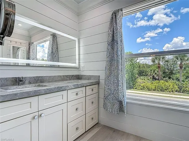 a bathroom with a granite countertop sink and window